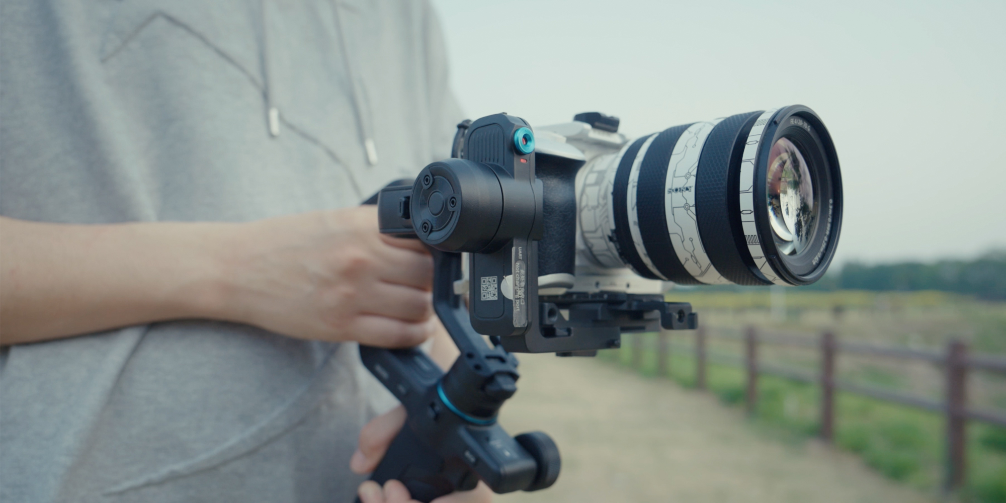 Gimbal ręczny FeiyuTech Scorp mini 3 Pro trzymany w rękach przez operatora w szarej bluzie