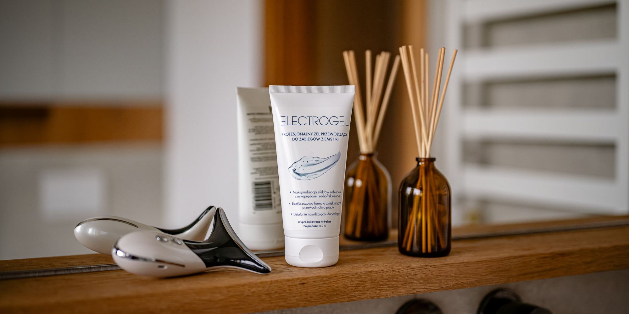 Żel przewodzący Humanas Electrogel - 150 ml ustawiony na półce obok dyfuzora zapachowego i urządzenia emitującego mikroprądy