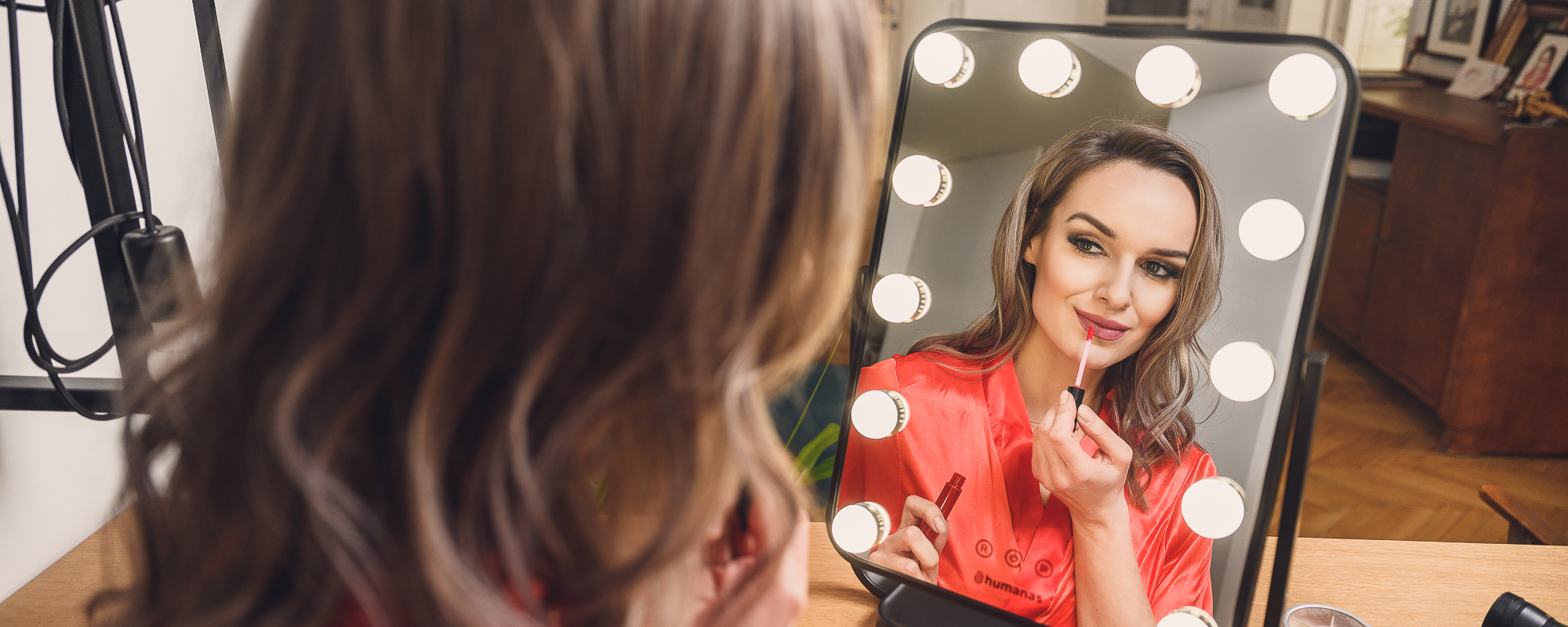 Młoda kobieta robi makijaż przed lustrem z oświetleniem LED