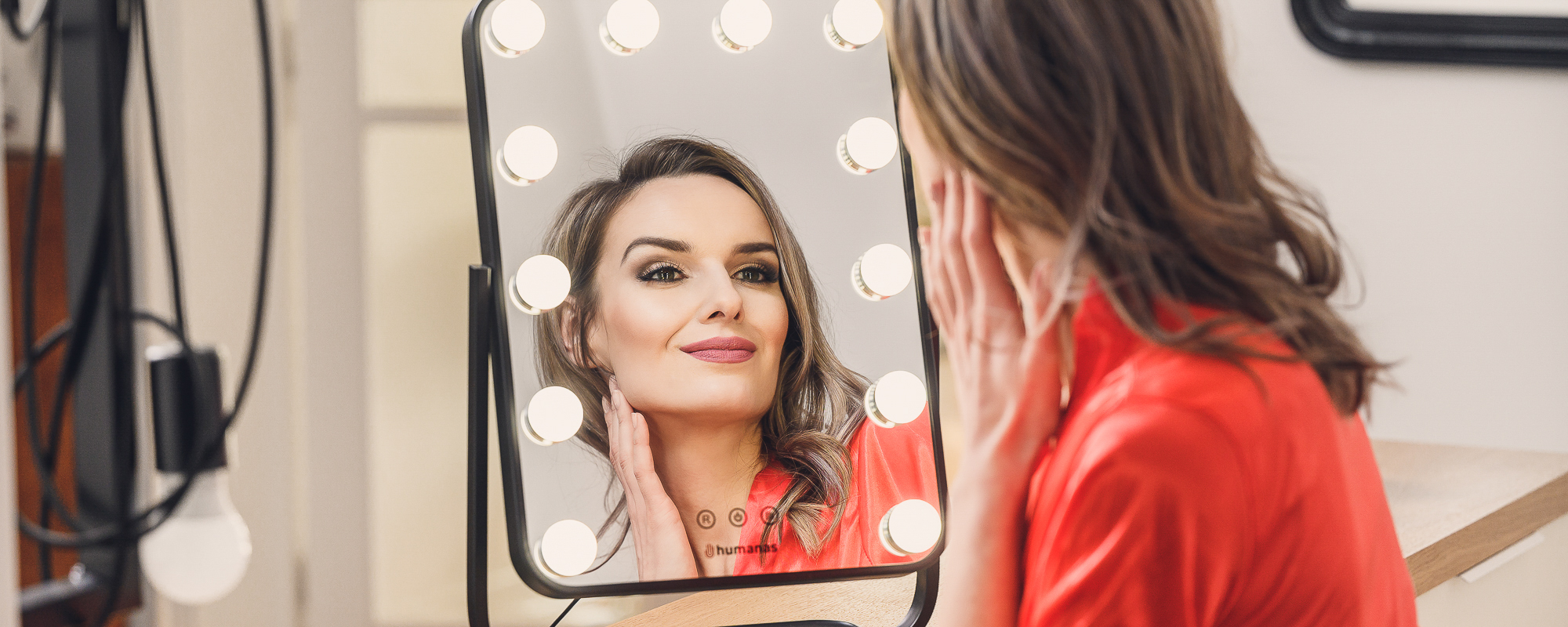 Young woman looking in the mirror with LED lighting