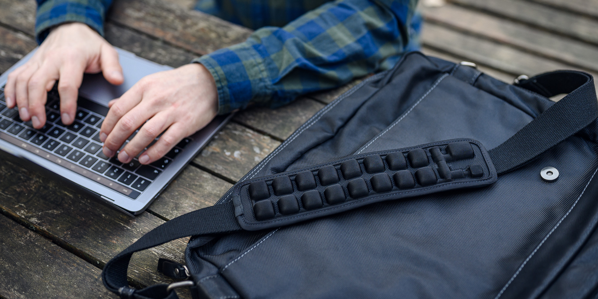 Le graphique montre le coussin gonflable Humanas R2 pour la sangle du sac - taille M à côté d'un homme utilisant un ordinateur portable.