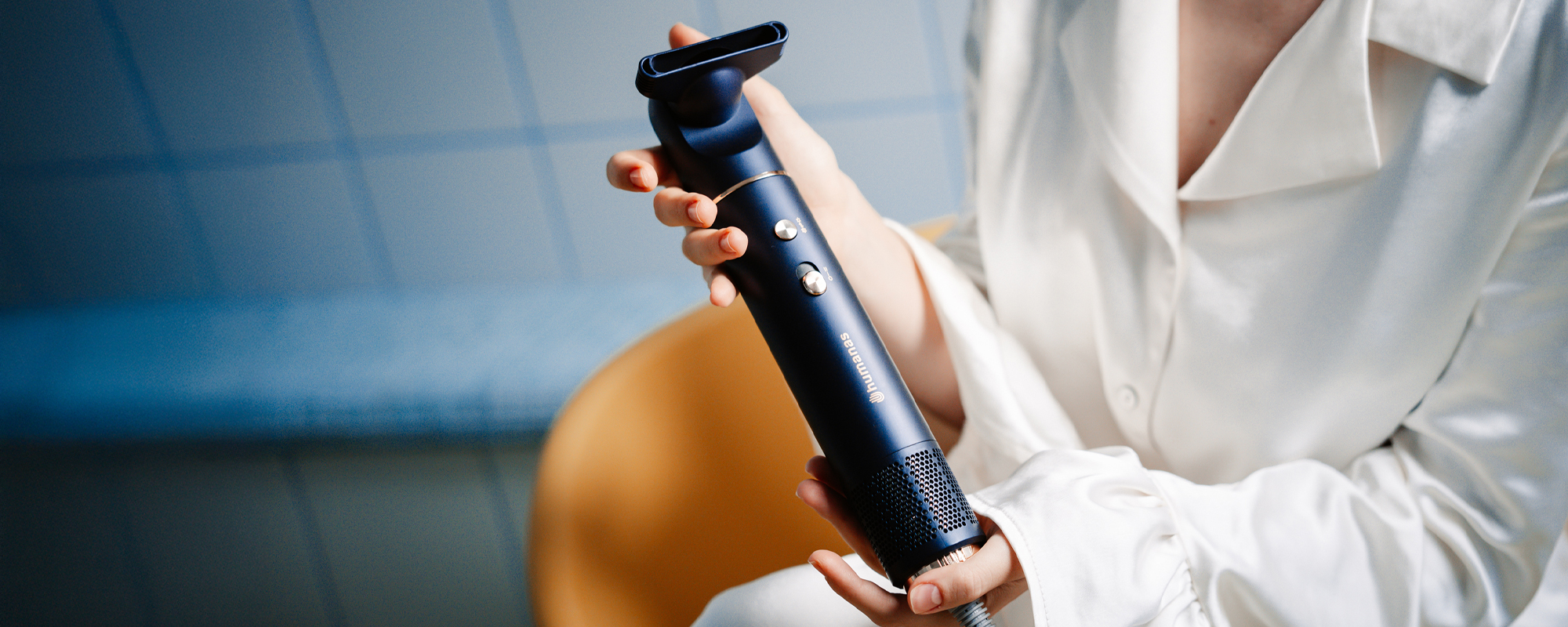 Kobieta trzymająca w dłoniach suszarkę do włosów z funkcją jonizowania Humanas AirTouch HD-AT05. W tle kafelki łazienkowe.