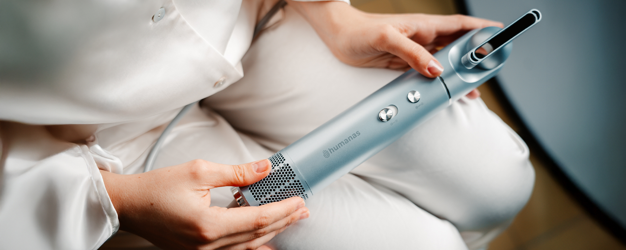 Kobieta trzymająca na kolanach suszarkę do włosów z funkcją jonizowania Humanas AirTouch HD-AT05.