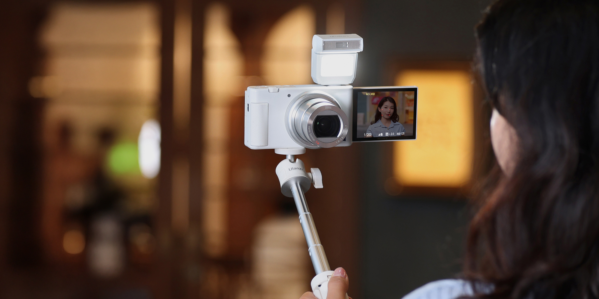 width=100% Lampa błyskowa Ulanzi SL03 - biała umieszczona na aparacie, który jest zamocowany na selfie sticku