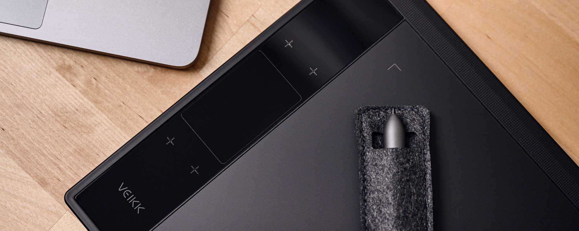 Zdjęcie - tablet graficzny Veikk A30 na jasnobrązowym biurku, a na nim piórko schowane w materiałowy pokrowiec