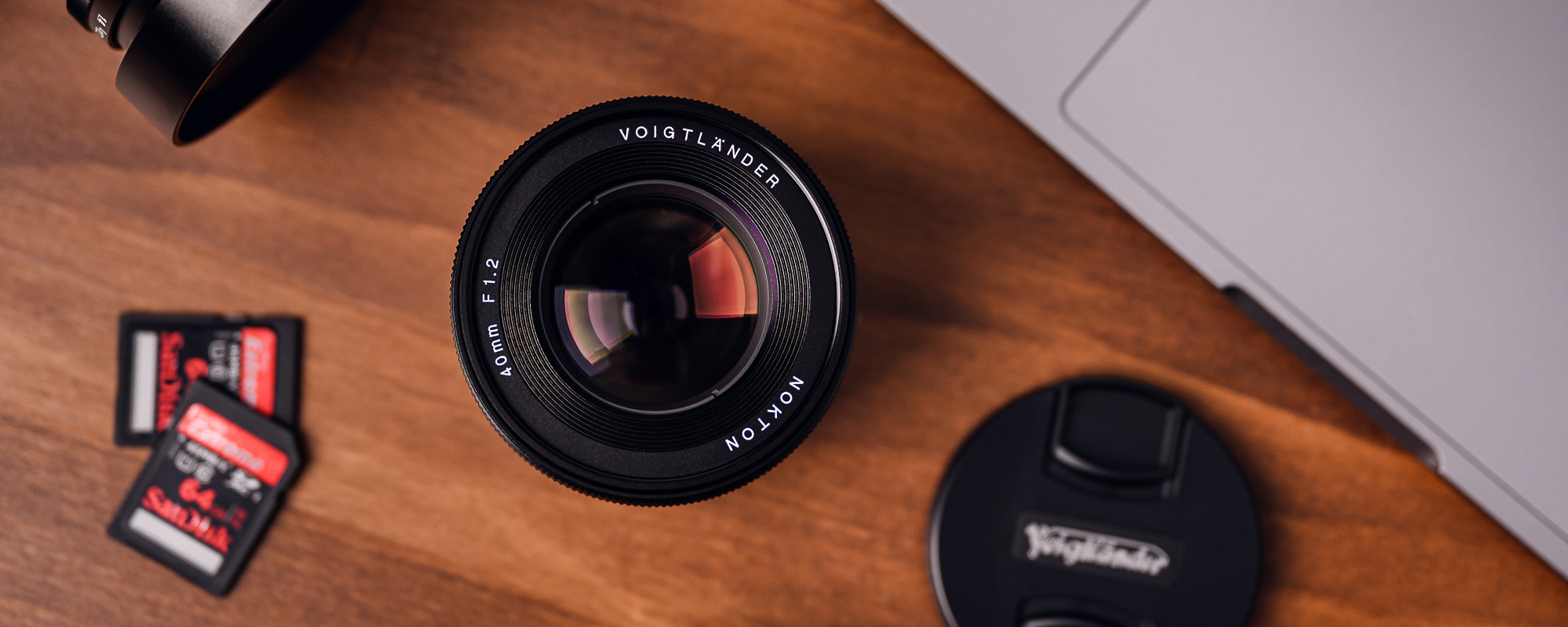 Obiektyw Voigtlander Nokton SE 40 mm f/1,2 do Sony E na drewnianym biurku widok na front obiektywu